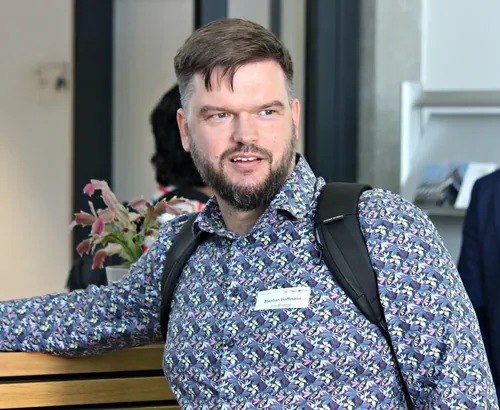 Teilnehmende stehen am Empfangstresen, Kaffee in der Hand.